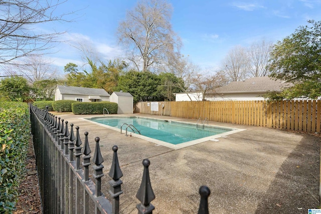 view of swimming pool featuring a storage unit, an outdoor structure, a fenced in pool, and a fenced backyard