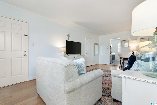 living area featuring baseboards, light wood finished floors, and ornamental molding