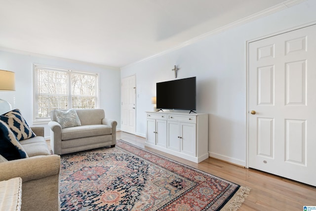 living room with light wood-style floors, baseboards, and ornamental molding