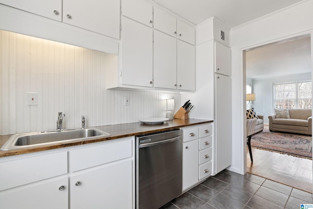 kitchen featuring dark tile patterned flooring, a sink, dark countertops, white cabinets, and dishwasher