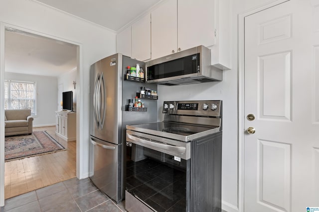 kitchen featuring baseboards, stainless steel appliances, white cabinets, crown molding, and tile patterned floors