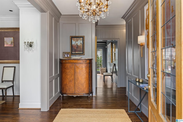 interior space featuring ornamental molding, dark wood-style flooring, a chandelier, and a decorative wall