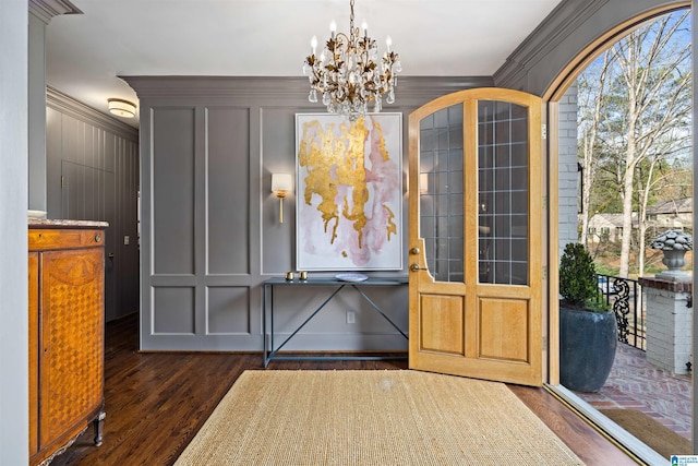 foyer entrance with a healthy amount of sunlight, ornamental molding, dark wood finished floors, and a decorative wall