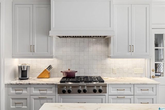 kitchen with light stone countertops, stainless steel gas stovetop, custom exhaust hood, and decorative backsplash