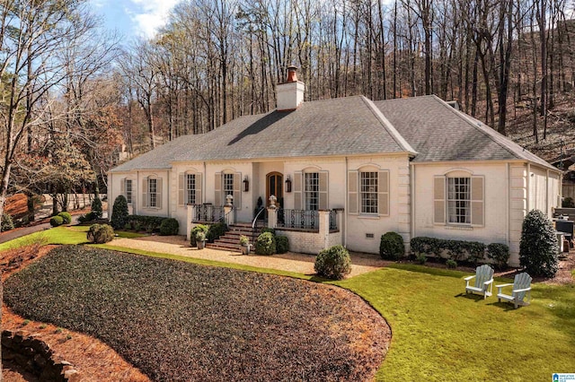 view of front of home featuring roof with shingles, a front yard, a porch, and brick siding