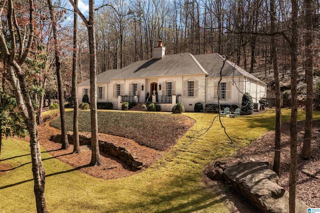 view of front of house with roof with shingles, a chimney, a front lawn, and stucco siding