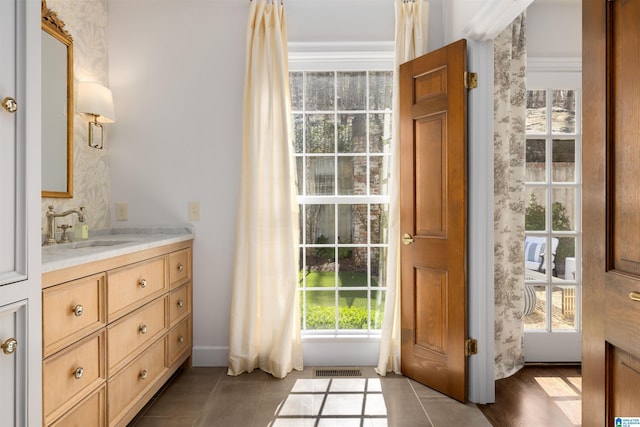 doorway to outside featuring dark tile patterned floors, a sink, and visible vents