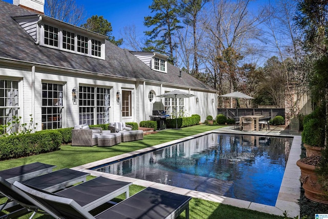 pool with a patio, an outdoor hangout area, fence, a grill, and a lawn