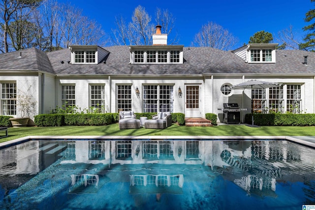 back of property featuring a chimney, an outdoor pool, and brick siding