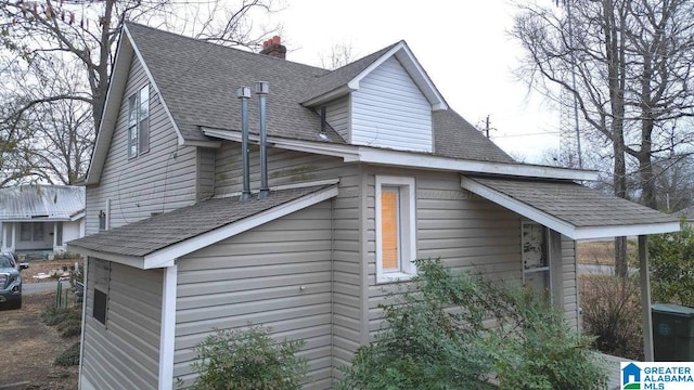 view of side of home featuring a shingled roof and a chimney