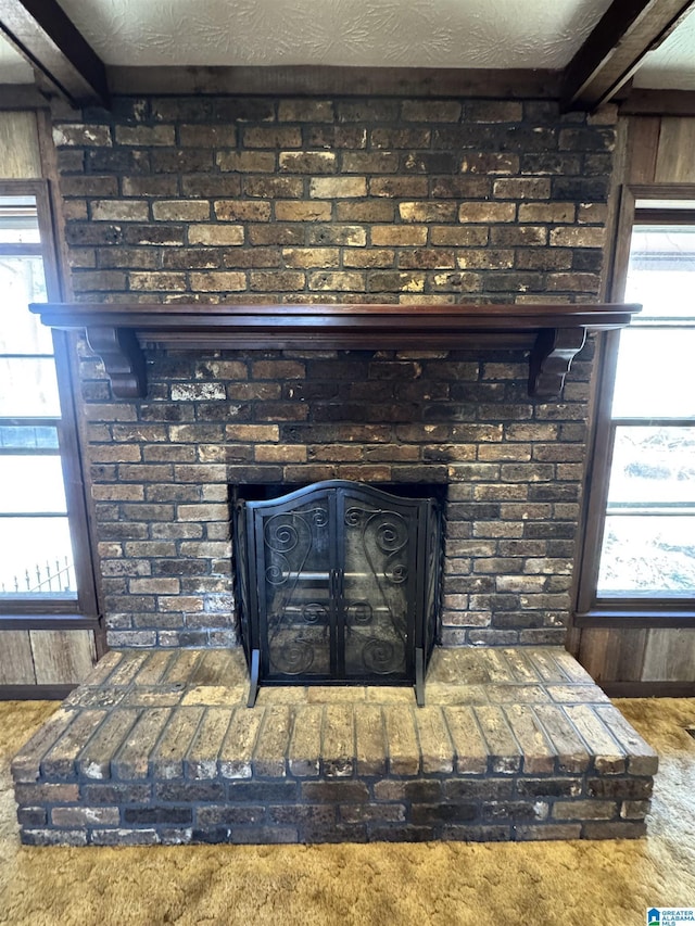 interior details featuring beam ceiling, wood walls, a fireplace, and a textured ceiling