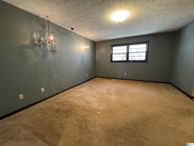 carpeted empty room with a textured ceiling and baseboards