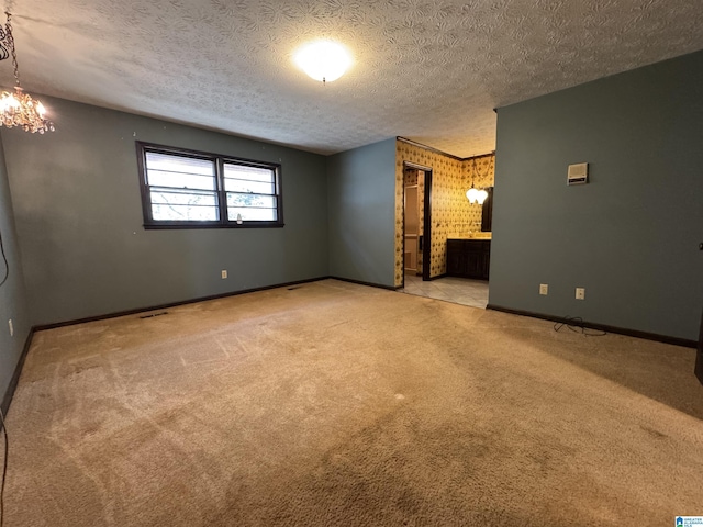 interior space featuring carpet flooring, ensuite bath, a textured ceiling, and baseboards