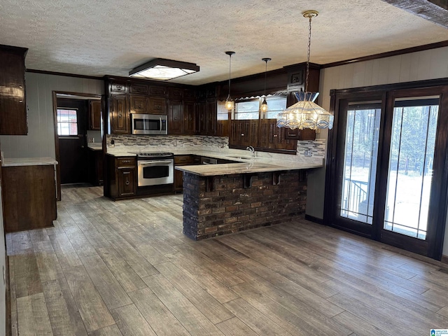 kitchen featuring a peninsula, a sink, light countertops, appliances with stainless steel finishes, and light wood finished floors