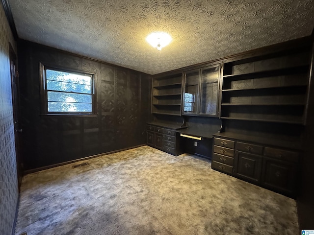 unfurnished office with carpet, visible vents, and a textured ceiling