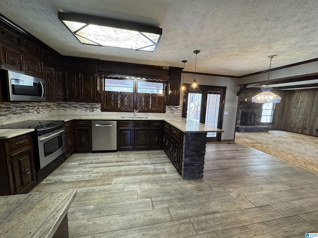 kitchen featuring light stone counters, backsplash, appliances with stainless steel finishes, light wood-type flooring, and a peninsula