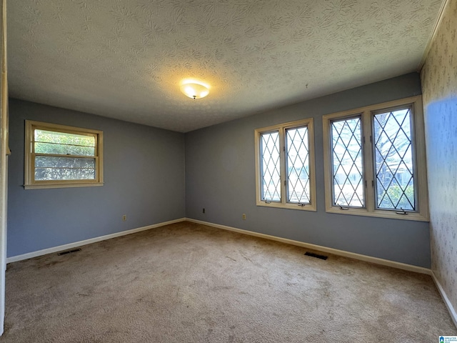 unfurnished room featuring plenty of natural light, carpet flooring, and visible vents