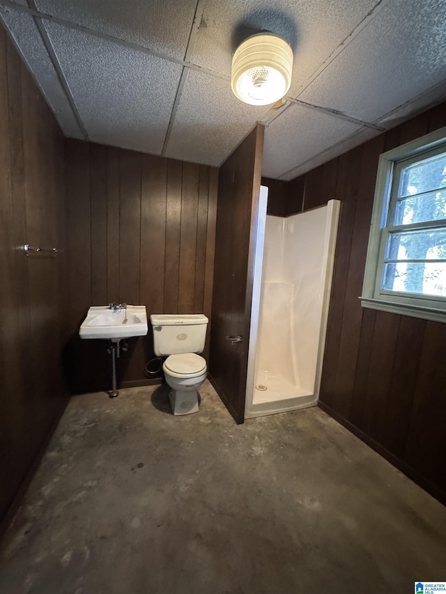 full bathroom with toilet, concrete floors, wooden walls, and a walk in shower