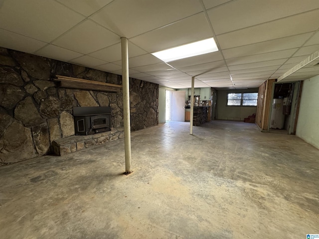 below grade area featuring gas water heater, a drop ceiling, and a wood stove