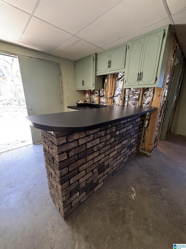 bar featuring concrete block wall, concrete floors, a bar, and a drop ceiling