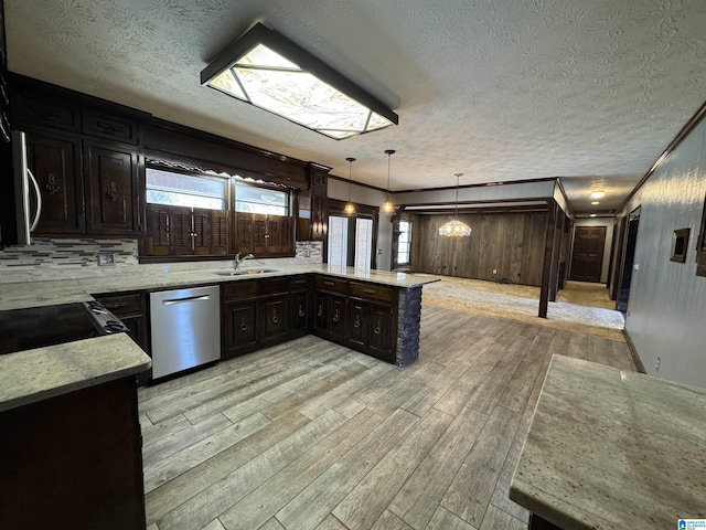 kitchen featuring a peninsula, a sink, light wood-type flooring, backsplash, and dishwasher