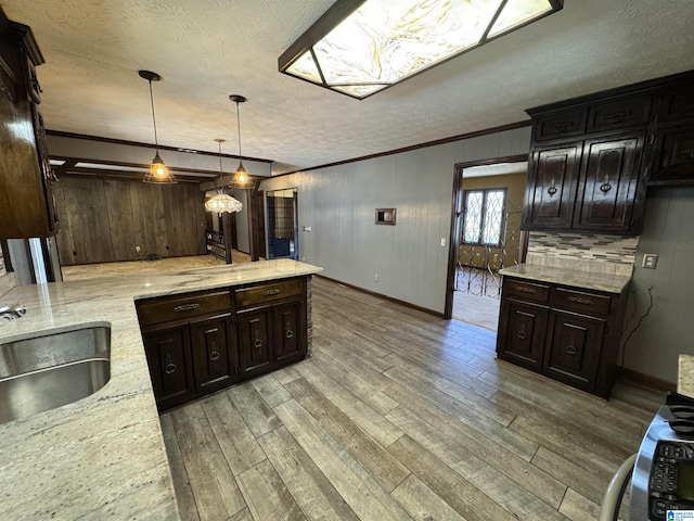 kitchen with ornamental molding, a sink, light wood-style flooring, and light stone counters