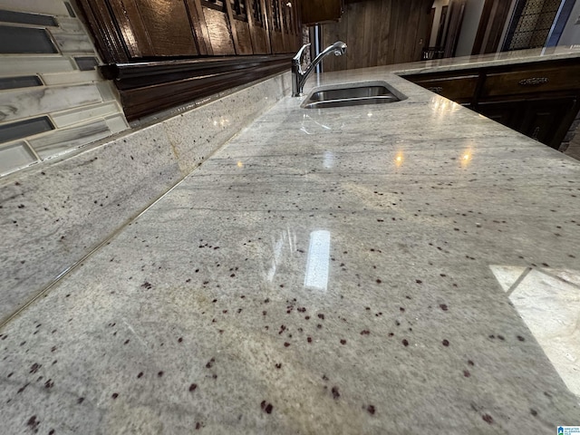 room details with a sink, dark brown cabinetry, and light stone countertops