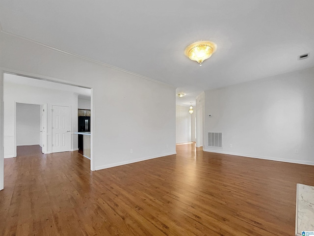 unfurnished living room with wood finished floors, visible vents, and baseboards