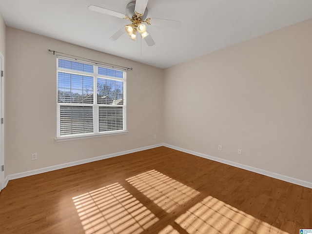 unfurnished room with ceiling fan, wood finished floors, and baseboards