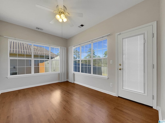 interior space with a ceiling fan, wood finished floors, visible vents, and baseboards