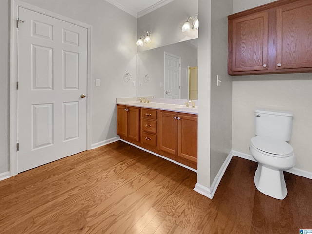 full bath with toilet, a sink, wood finished floors, ornamental molding, and double vanity