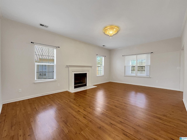 unfurnished living room featuring baseboards, a fireplace, visible vents, and wood finished floors