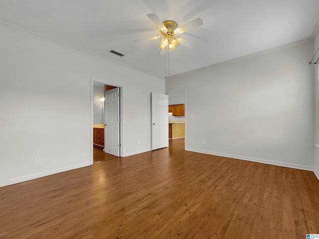 empty room featuring visible vents, ornamental molding, ceiling fan, wood finished floors, and baseboards