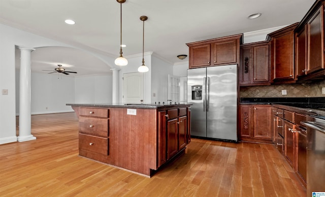 kitchen featuring arched walkways, stainless steel appliances, a ceiling fan, decorative backsplash, and ornate columns