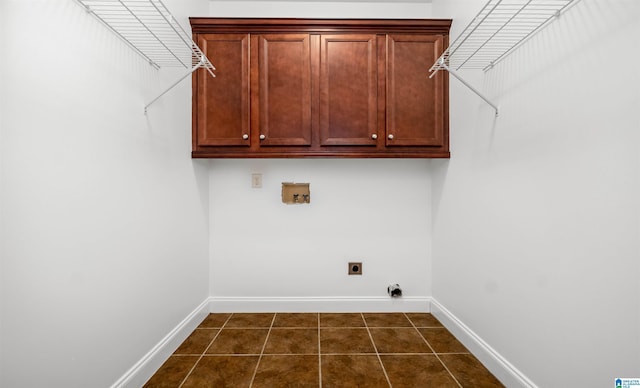 clothes washing area with washer hookup, cabinet space, hookup for an electric dryer, dark tile patterned flooring, and baseboards