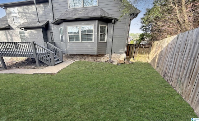 back of house featuring a yard, a shingled roof, a fenced backyard, and a wooden deck