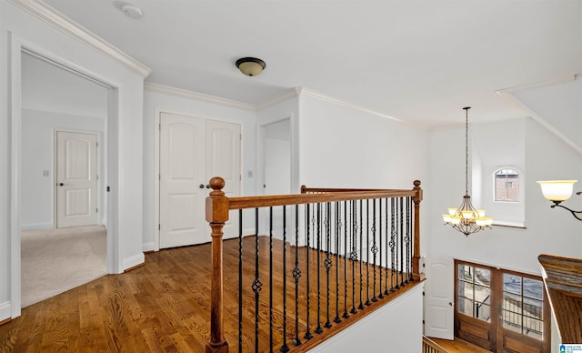 corridor with crown molding, a chandelier, wood finished floors, and an upstairs landing