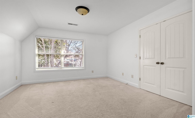 unfurnished bedroom with lofted ceiling, carpet flooring, visible vents, and baseboards