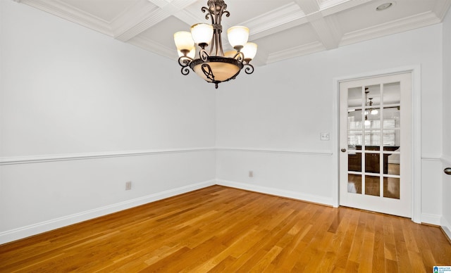 empty room with light wood-style floors, coffered ceiling, and crown molding