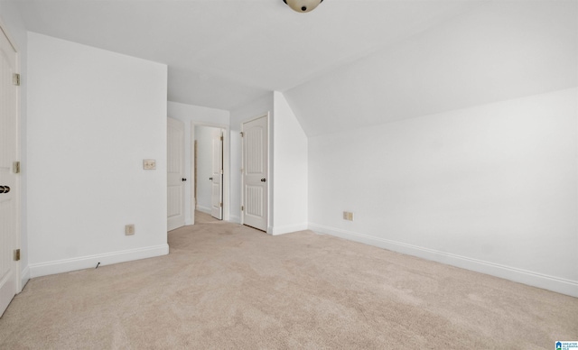 additional living space with lofted ceiling, baseboards, and light colored carpet