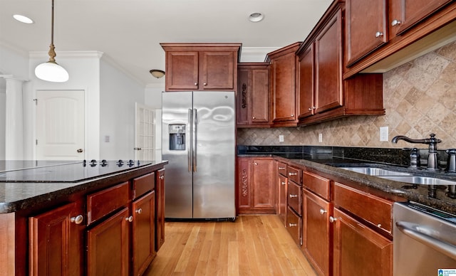 kitchen featuring light wood finished floors, stainless steel appliances, backsplash, ornamental molding, and a sink