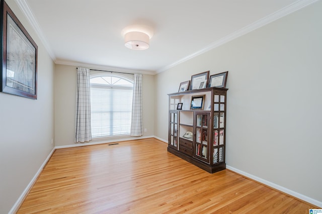 empty room with ornamental molding, baseboards, and wood finished floors