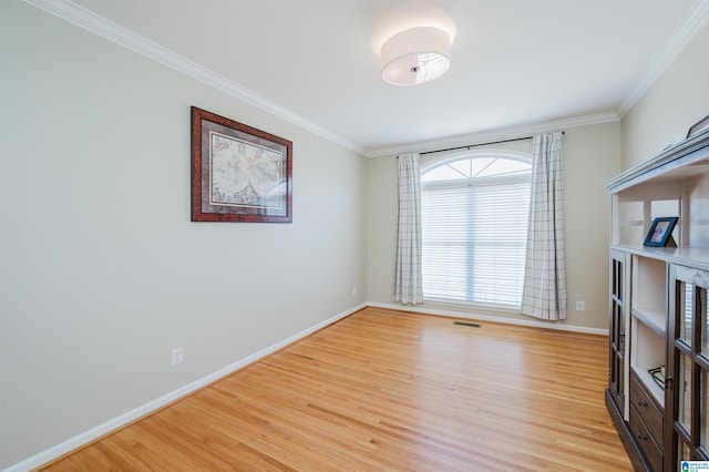 unfurnished room featuring baseboards, light wood-style flooring, and crown molding