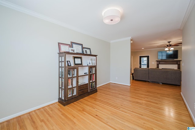 spare room featuring baseboards, a fireplace, light wood-style flooring, and crown molding