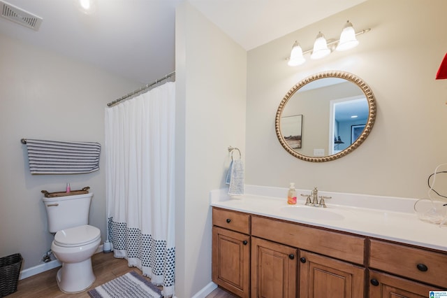 full bathroom with toilet, wood finished floors, vanity, visible vents, and baseboards