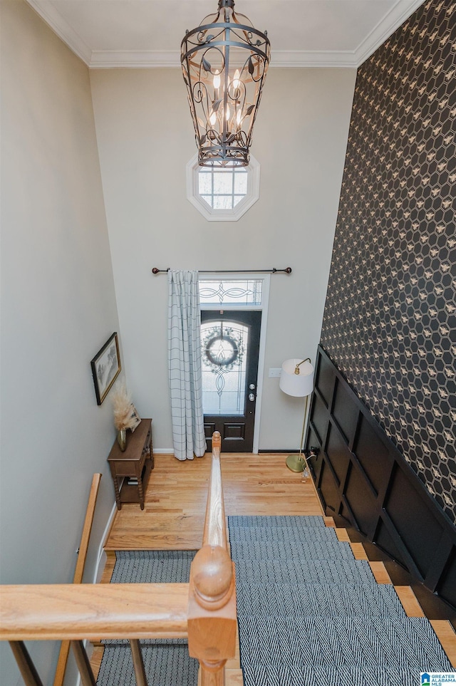 entrance foyer featuring a notable chandelier, a high ceiling, ornamental molding, wood finished floors, and baseboards