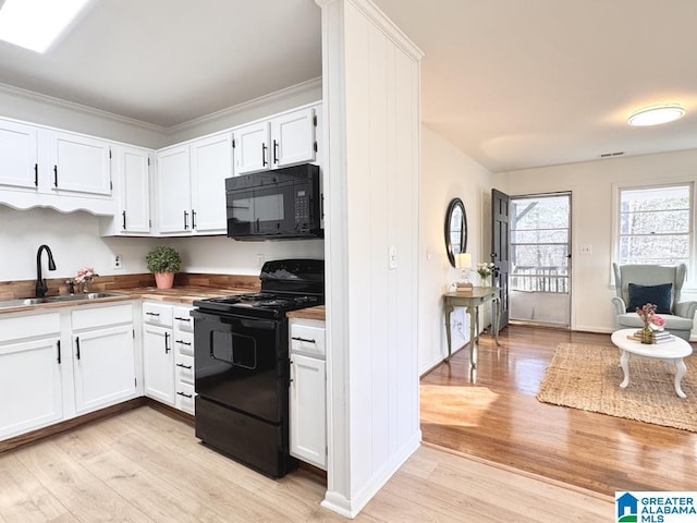 kitchen featuring light wood-type flooring, black appliances, white cabinetry, and a sink