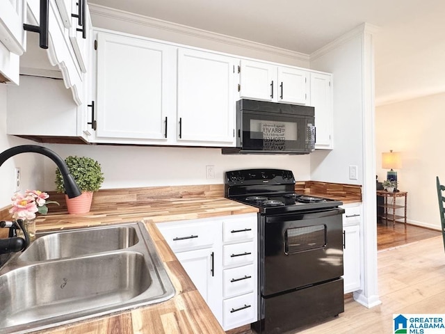 kitchen with light wood finished floors, white cabinets, a sink, butcher block countertops, and black appliances