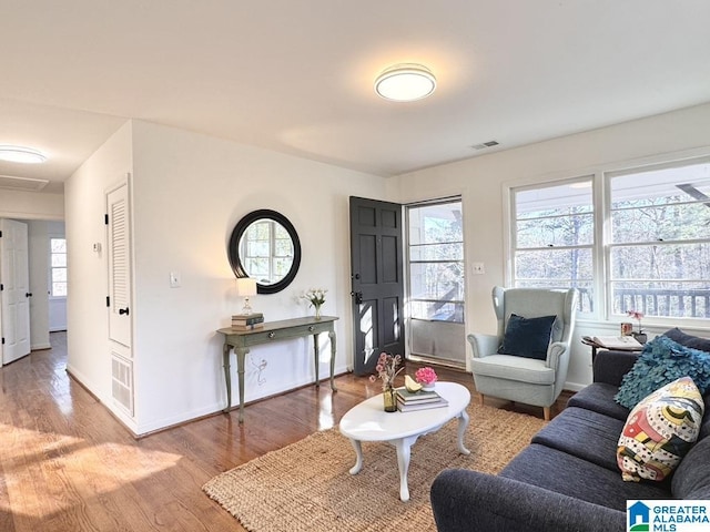 living room with wood finished floors, visible vents, and baseboards