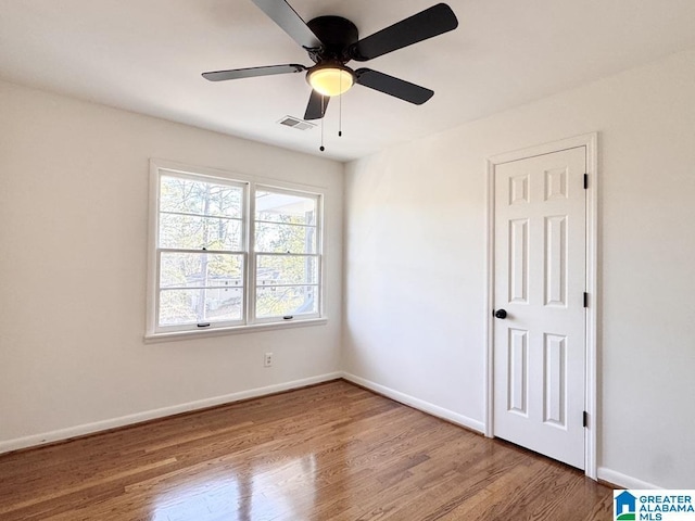 spare room featuring a ceiling fan, wood finished floors, visible vents, and baseboards